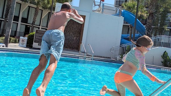 Jayden and Olivia mid-air, jumping into a pool