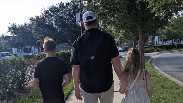 Andreas walking down a Florida sidewalk holding hands with Olivia, Jayden alongside