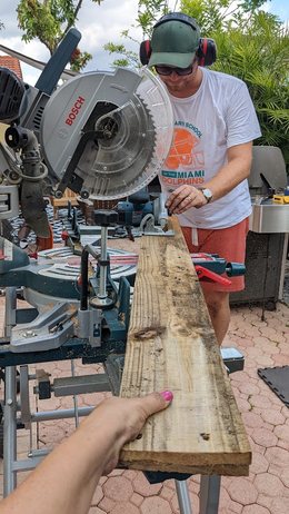 Andreas at a mitre saw cutting a board, ear defenders on